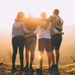 group of four people looking at a sunset