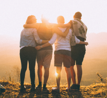 group of four people looking at a sunset