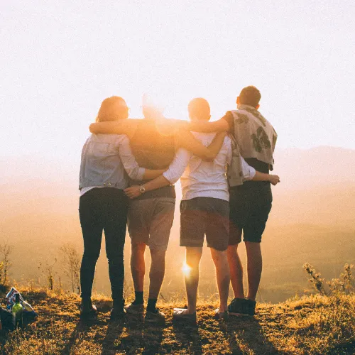 group of four people looking at a sunset